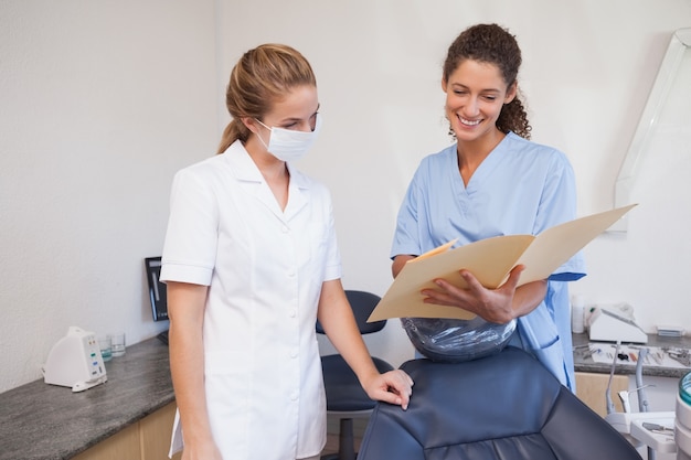 Dentista y asistente estudiando carpetas