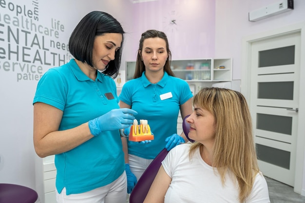 una dentista y una asistente tratan los dientes de un paciente que vino con problemas en la cavidad oral concepto de dentista dientes y su tratamiento dentista femenina