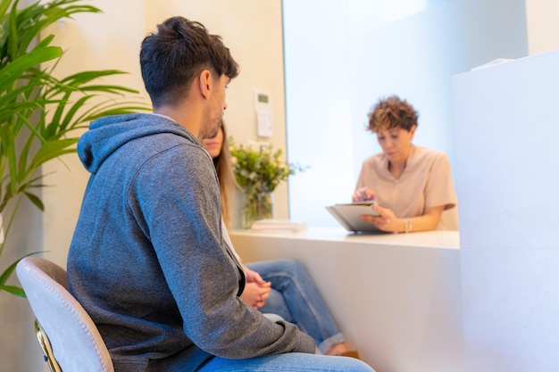 Dentista atendiendo a una pareja en la recepción de una clínica