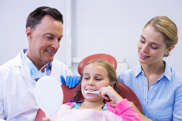 Dentista auxiliando paciente jovem enquanto escova os dentes