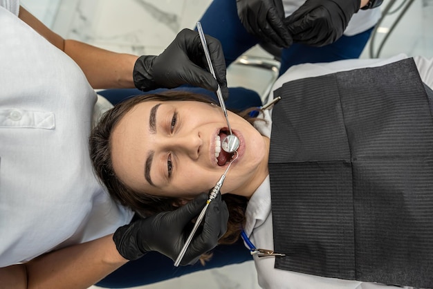 Foto el dentista con la ayuda de un asistente realiza un examen profesional de la cavidad oral del paciente