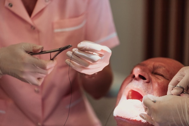 Un dentista con la ayuda de un colega realiza una operación en la mandíbula de un paciente anciano en una clínica dental moderna. foto de alta calidad