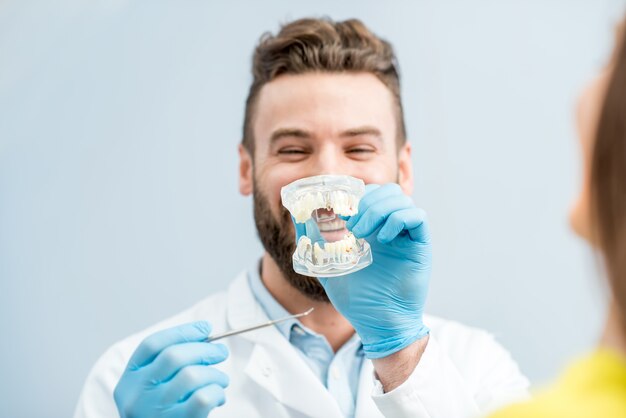 Dentista bonito consultando uma paciente com mandíbula artificial no consultório odontológico