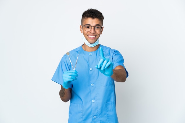 Dentista brasileño sosteniendo la herramienta aislada mostrando y levantando un dedo