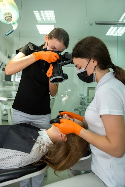 Dentista con cámara especial haciendo tomas profesionales de la boca del paciente después de un tratamiento prolongado. Cuidado de la salud