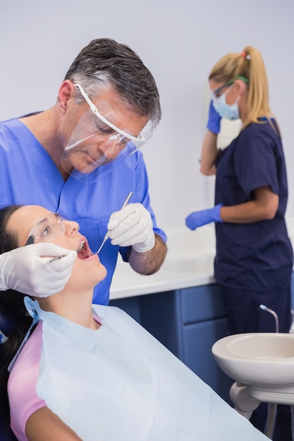 Dentista con careta y examinando a un paciente