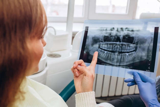 El dentista de la casa familiar muestra una radiografía. Una mujer joven sentada en una recepción cerca de un dentista. Dentista niña