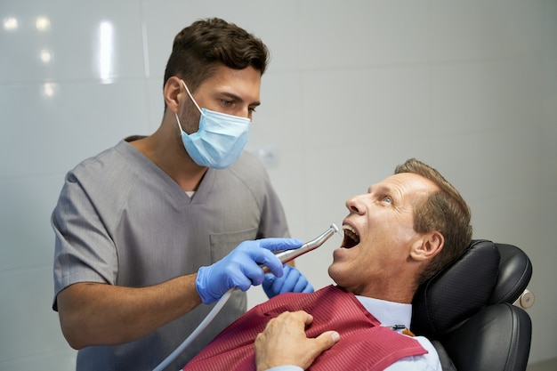 Dentista certificado que trata a su paciente en la clínica.