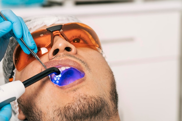 Dentista clareando os dentes de um paciente com laser em uma clínica odontológica