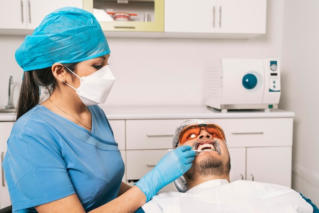 Dentista clareando os dentes de um paciente em uma clínica odontológica