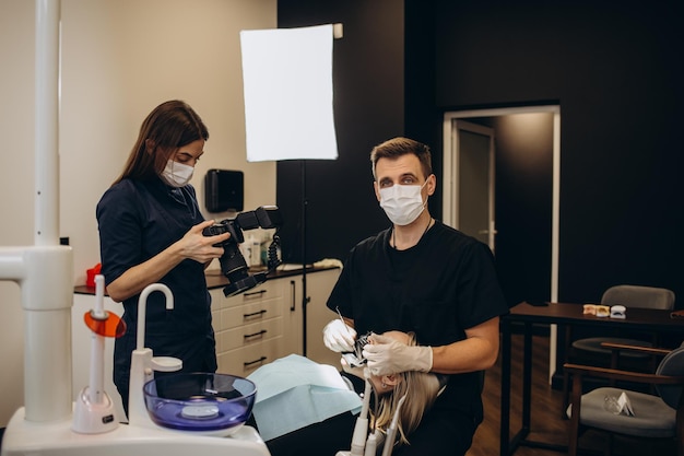 Dentista en la clínica dental del trabajo Joven doctora tomando fotografías de los dientes y la mandíbula del paciente después de un tratamiento exitoso