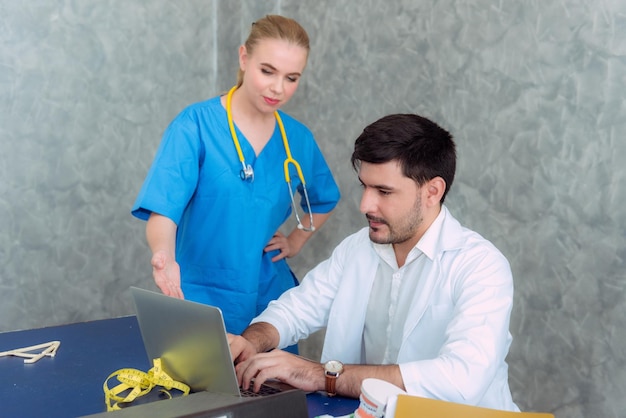 Dentista con un colega usando una computadora portátil en la clínica