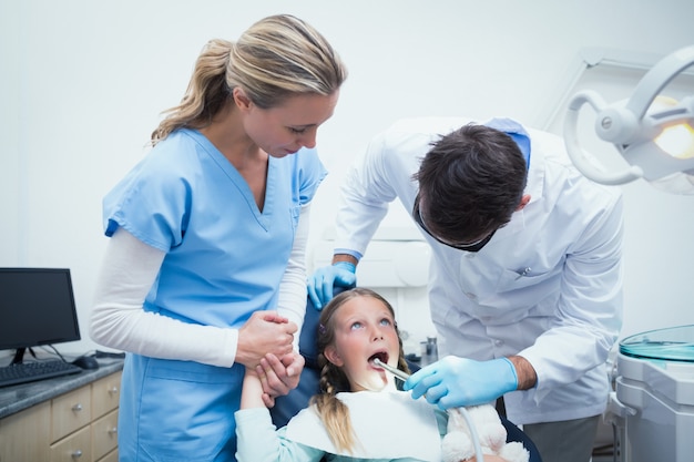 Dentista com assistente de dentes das meninas examinadoras