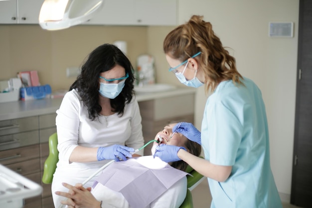 Foto dentista en el consultorio dental hablando con una paciente femenina y preparándose para el tratamiento