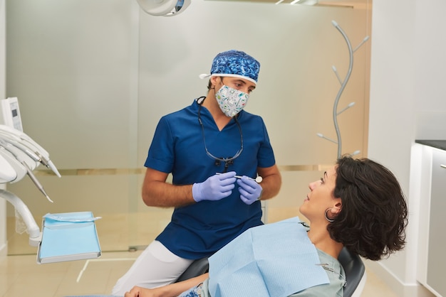 Dentista conversando com uma linda paciente no consultório odontológico.