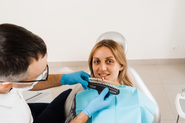 Foto dentista de clareamento dental trabalhando com guia de tons de cor dos dentes odontologia médico verificando amostras de correspondência de cores dos dentes na clínica odontológica