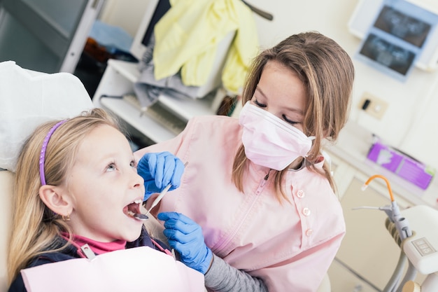 Dentista de garotinhas e paciente durante exame dentário.