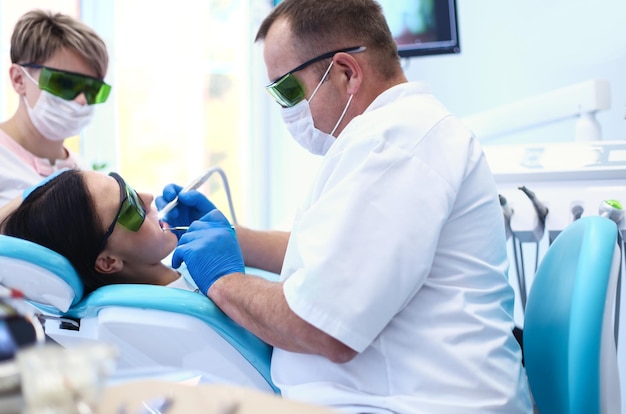 Dentista de homem trabalhando nos dentes de seus pacientes