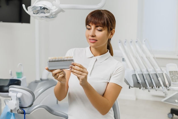 Foto el dentista demuestra la guía de tonos de color de los dientes para blanquear los dientes primer plano de la combinación de colores de los dientes