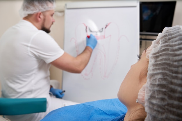 Foto dentista dibujo imagen de diente en la pizarra en el consultorio del dentista