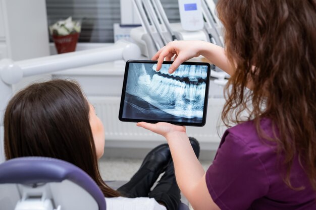 Una dentista discute las opciones de tratamiento con el paciente mientras muestra la radiografía