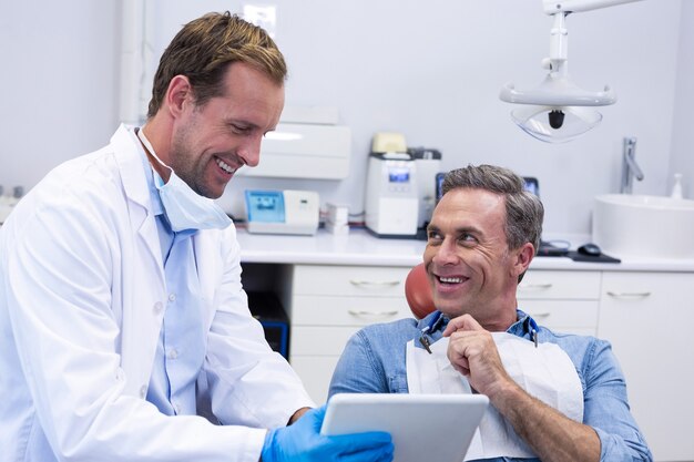 Dentista discutindo sobre tablet digital com paciente do sexo masculino