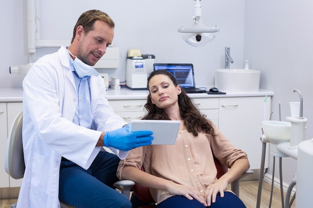 Dentista discutindo sobre tablet digital com paciente