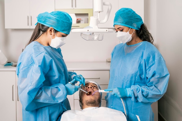 Dentista e assistente consertando e limpando a boca de um paciente em uma clínica odontológica