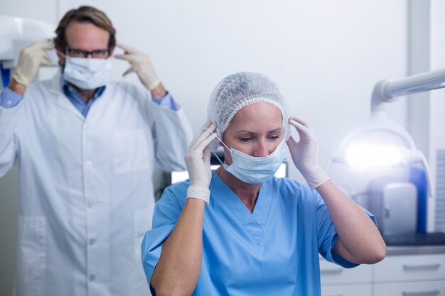 Dentista e assistente dental usando máscara cirúrgica