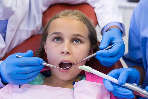 Dentista e enfermeira examinando um jovem paciente com ferramentas