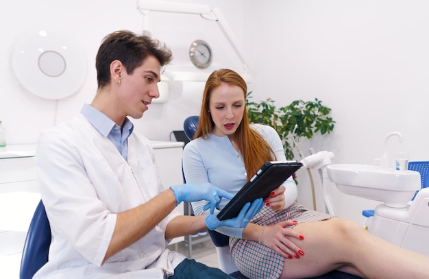 Dentista e paciente lendo dados no tablet