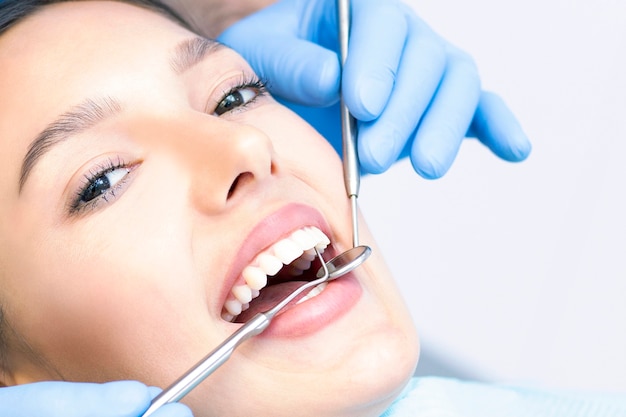Dentista e paciente no consultório odontológico. Mulher tendo dentes examinados por dentistas