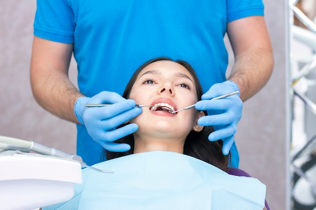 Dentista e paciente no consultório odontológico. mulher tendo dentes examinados por dentistas