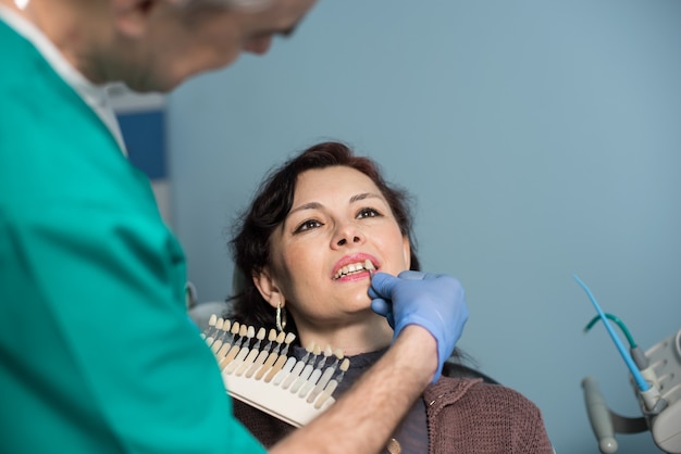 Dentista eligiendo el color de los dientes para un paciente