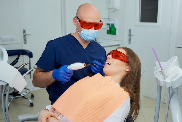 dentista em luvas médicas uniformes e descartáveis com um paciente no consultório do dentista