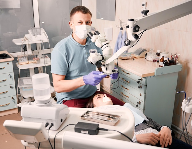 Dentista em máscara facial médica tratando os dentes do paciente no consultório odontológico