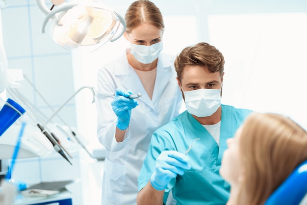 Un dentista y una enfermera están tratando al paciente.