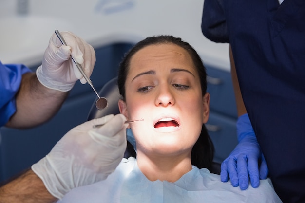 Dentista y enfermera examinando a un paciente asustado