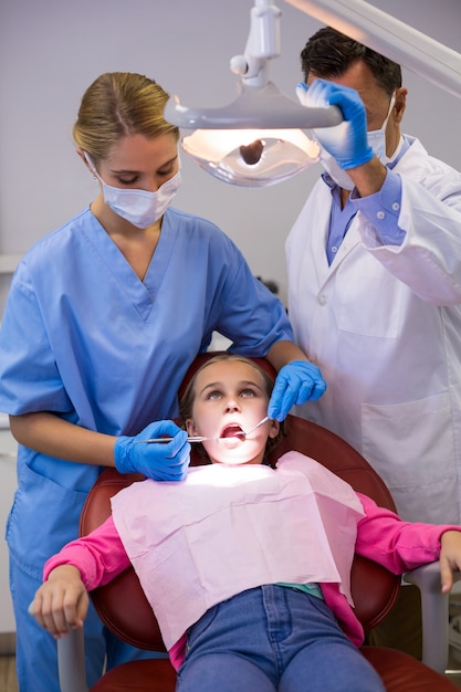 Dentista y enfermera examinando a un paciente joven con herramientas