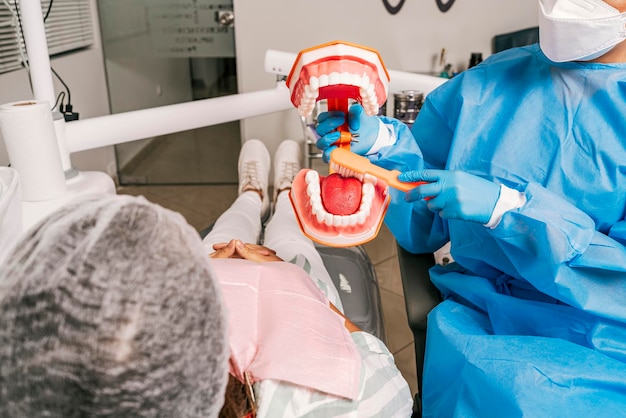 Dentista enseñando cómo limpiar la boca usando un prototipo a un paciente