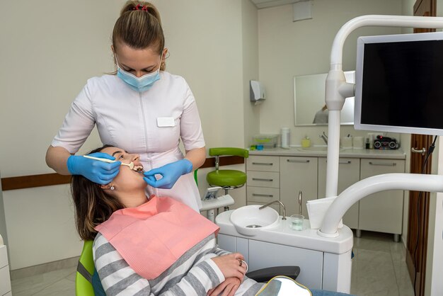 Foto dentista escogiendo muestras de color para el tratamiento de blanqueo su mujer cliente mejor resultado