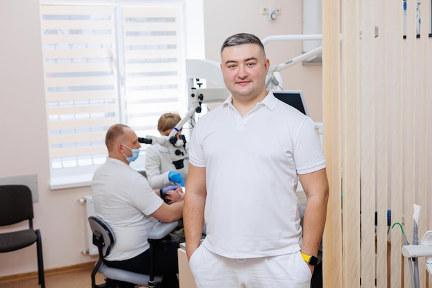 El dentista está en su consultorio dental Un dentista con uniforme blanco trata los dientes de un paciente con un microscopio dental Consultorio dental