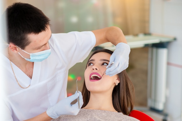 El dentista está tratando los dientes con una hermosa niña.