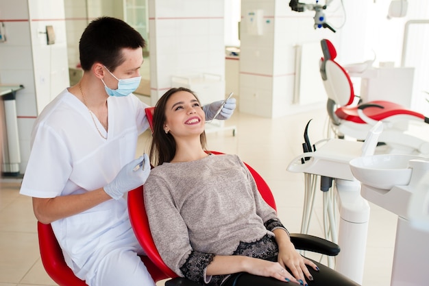 El dentista está tratando los dientes con una mujer hermosa.