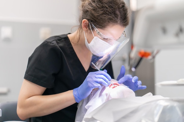 El dentista examina la boca y los dientes del paciente utilizando un explorador dental.