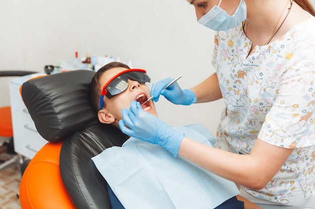 El dentista examina los dientes de un niño de 13 años en la clínica de odontología pediátrica