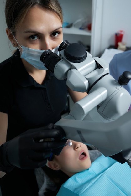 El dentista examina los dientes del niño con un microscopio. Equipo dental profesional.