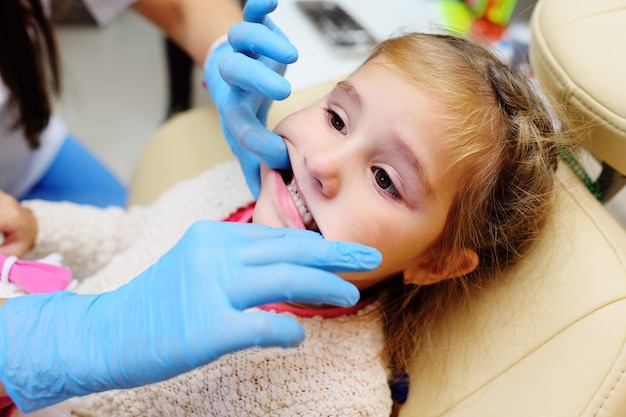 El dentista examina los dientes de un niño en una silla dental.