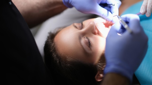 El dentista examina los dientes del paciente en el dentista y el instrumento dental