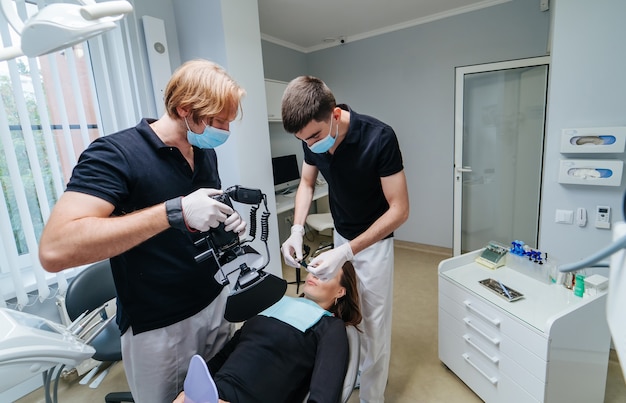 El dentista examina los dientes del paciente con un microscopio dental.